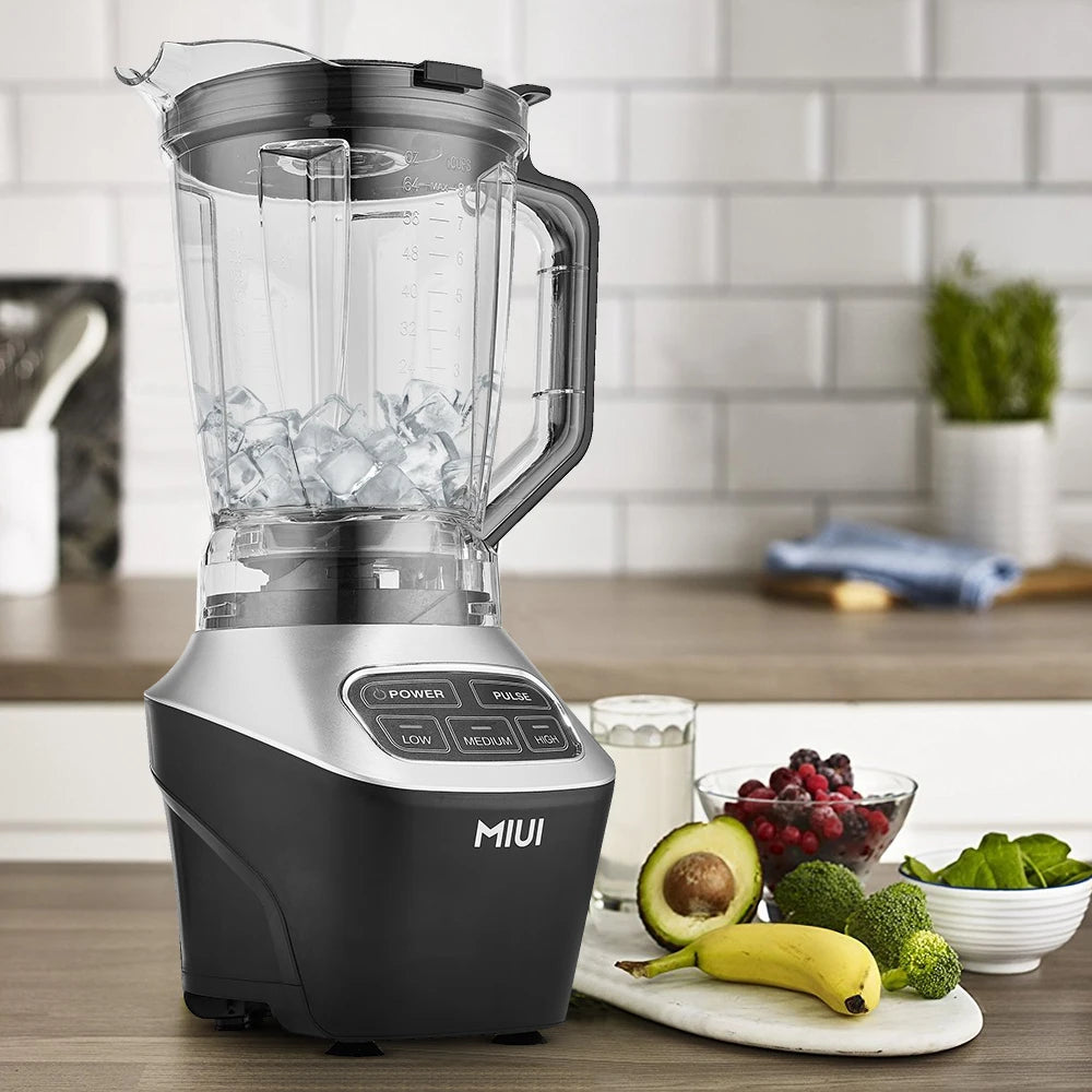 Blender on a kitchen counter with fruits and vegetables, featuring the brand 'MIUI'.